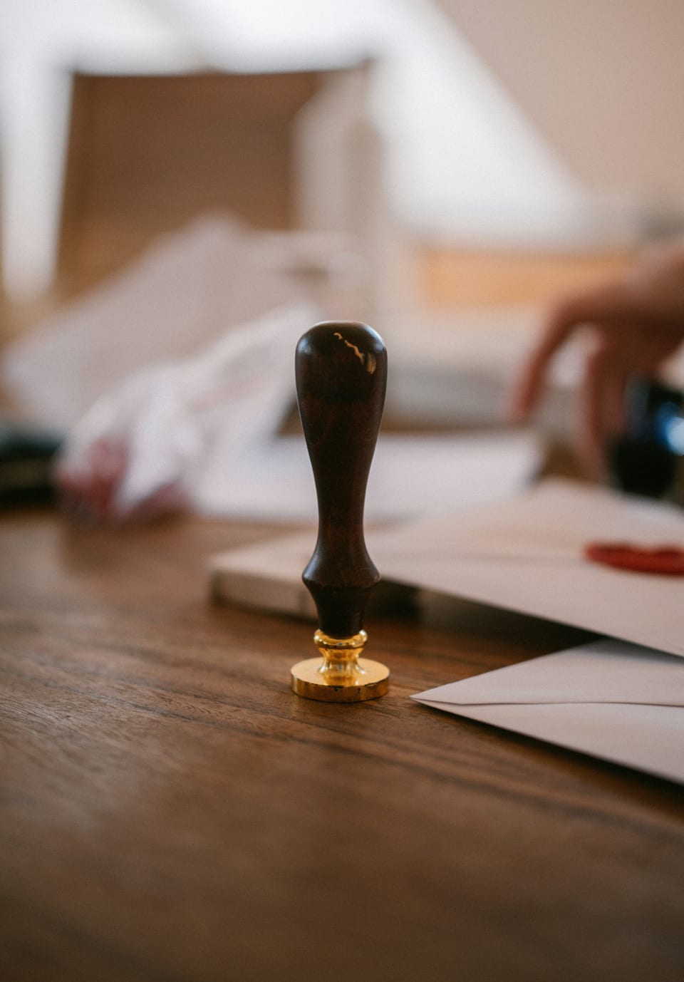 Decorative wooden-handled stamp beside paper and an envelope on a desk